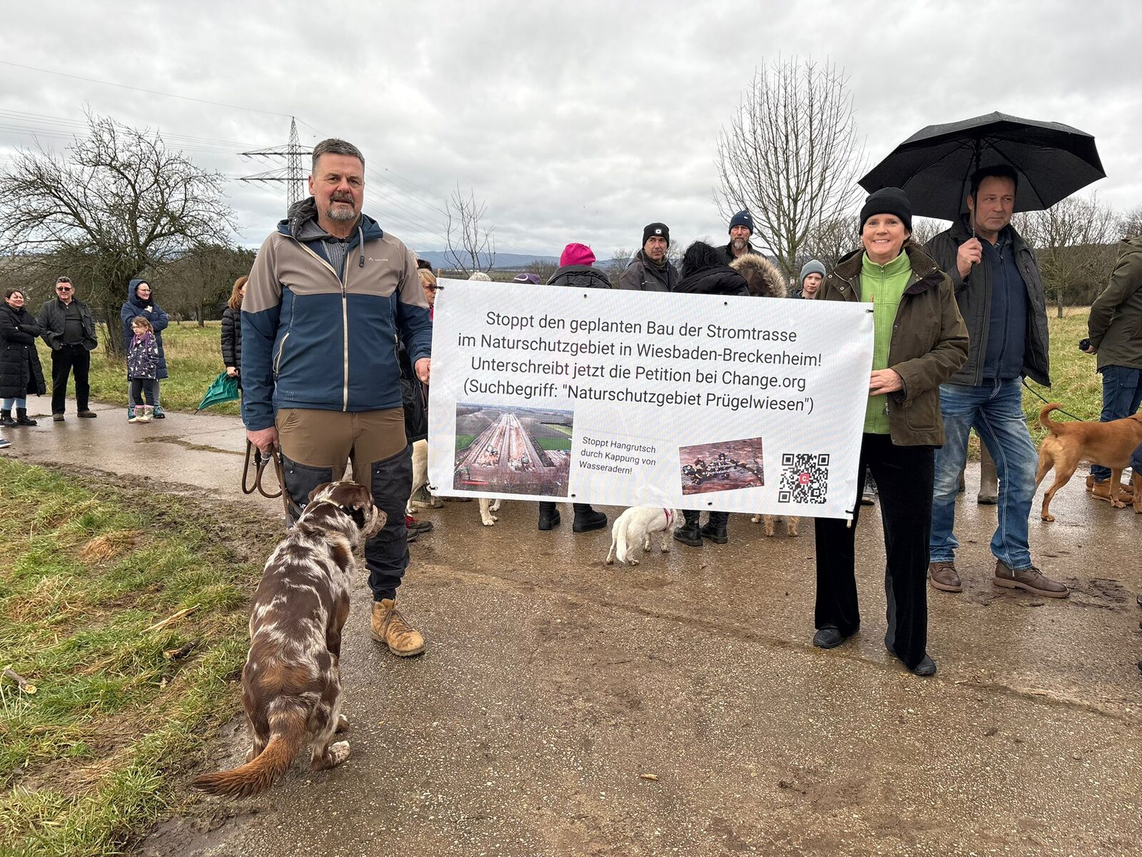 Teilnehmende halten ein Plakat mit Petition gegen den geplanten Trassenbau